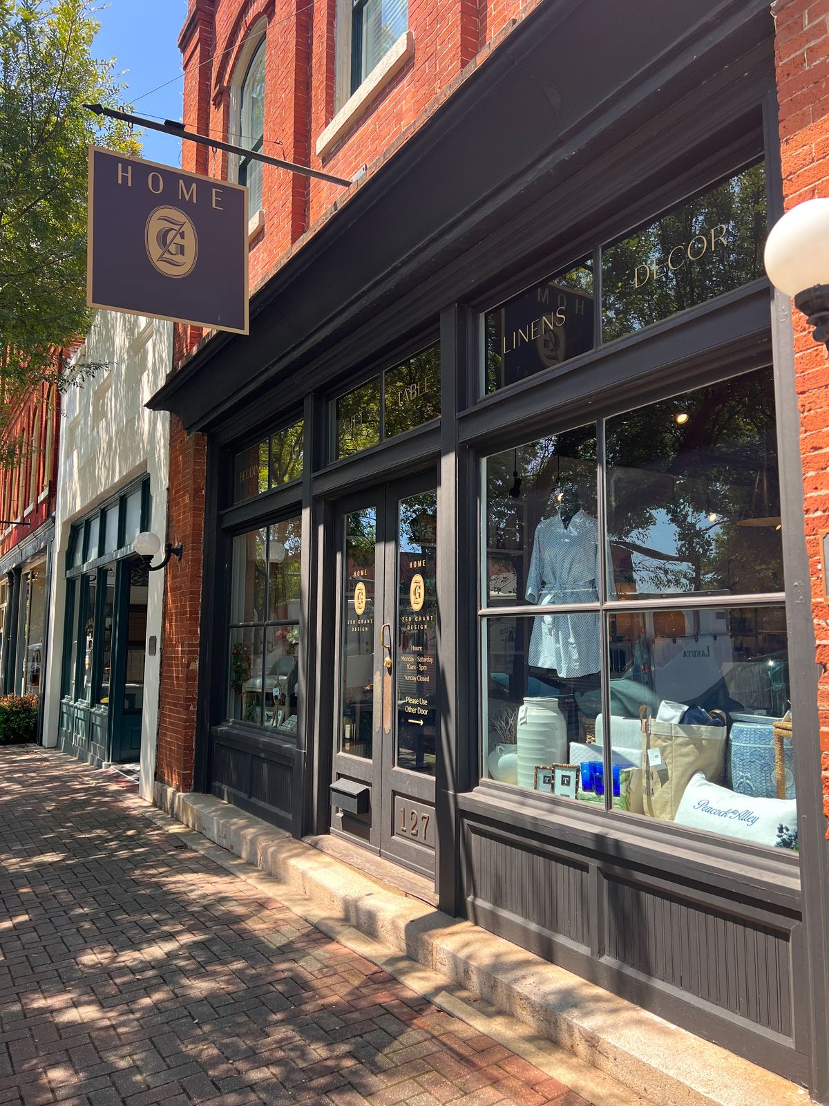 A sunlit storefront with a hanging sign on a small-town street