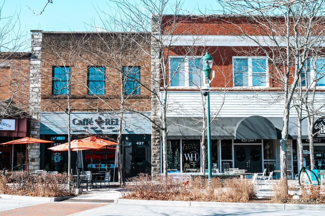 Storefronts with orange café umbrellas on a small-town sidewalk